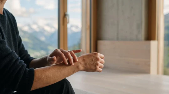 Main effleurant la peau en lumière naturelle, évoquant la précision et la douceur des soins biotechnologiques suisses